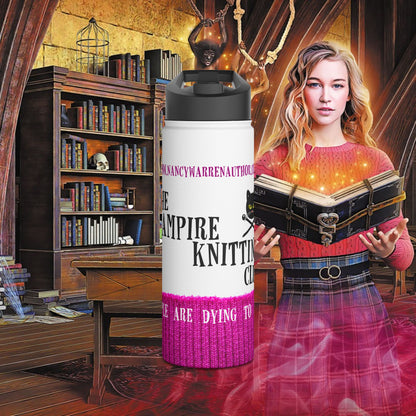 A white insulated tumbler with a black lid and pink-and-purple printed text stands in front of a fantasy-style scene showing a woman holding an open glowing book in a library-like room.